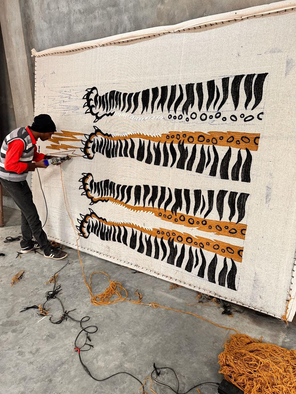 man hand-tufting wool rugs with a hand held tufting gun