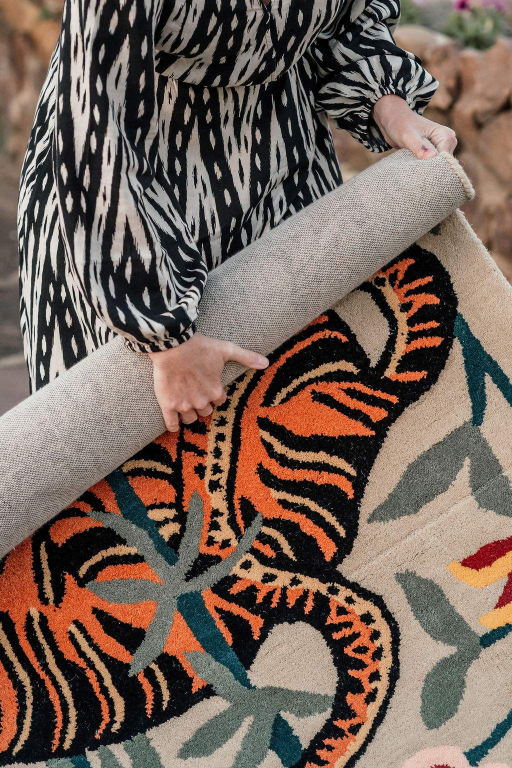 Person holding a colorful rug with tiger design
