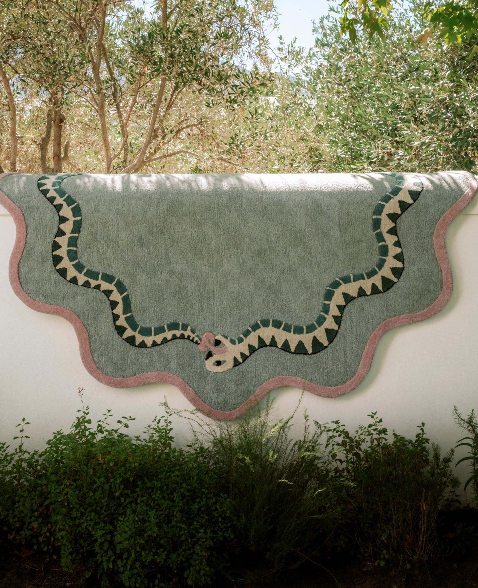 Decorative rug with snake design on a white wall outdoors in south africa