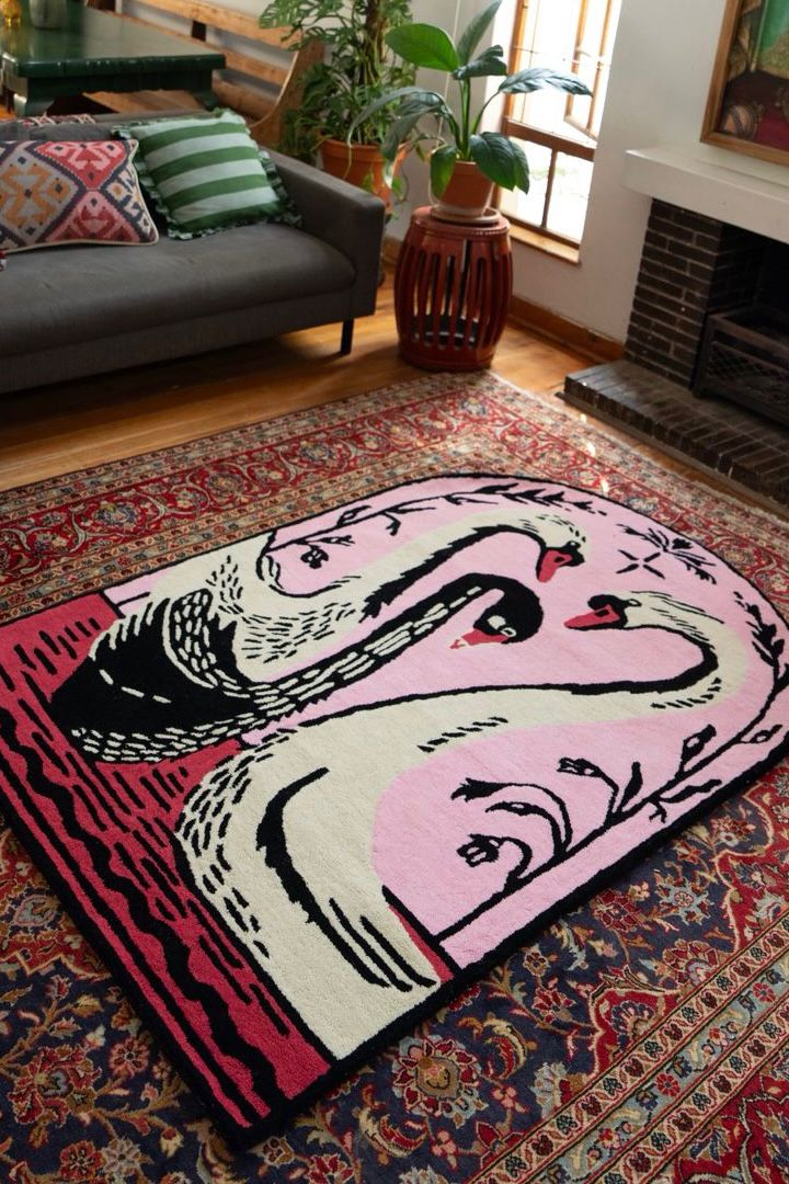 Colorful abstract pink and red rug with swan design on a patterned rug in a living room.