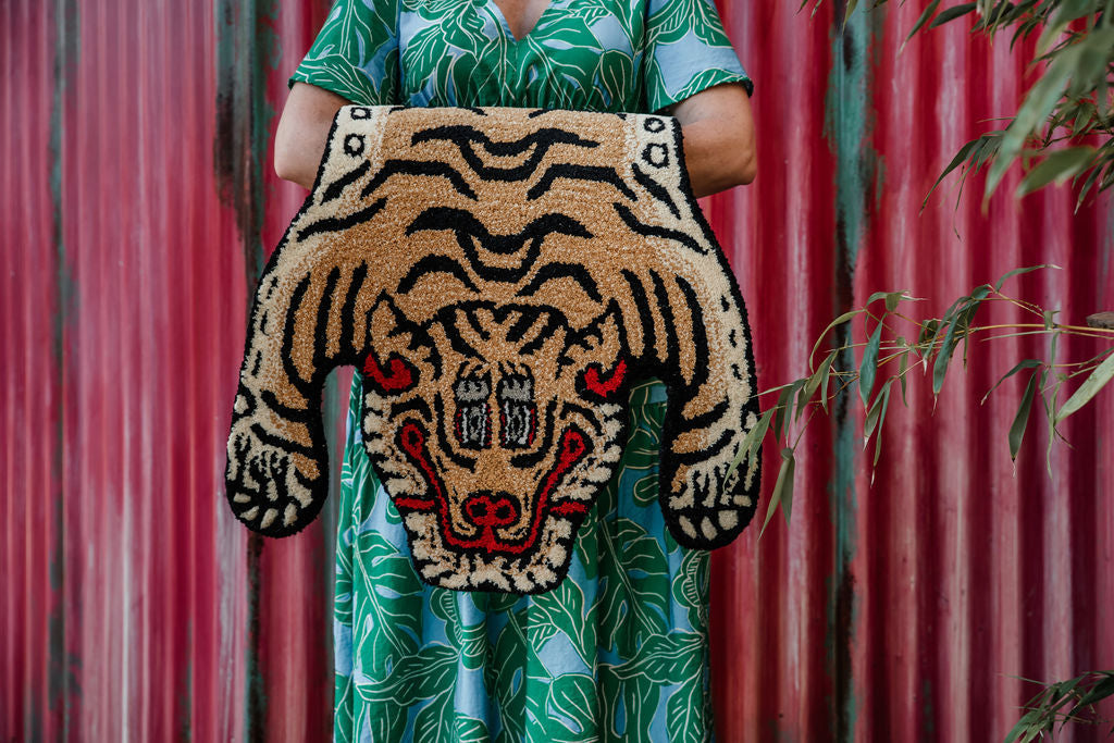 lady holding a small tibetan tiger wool rug
