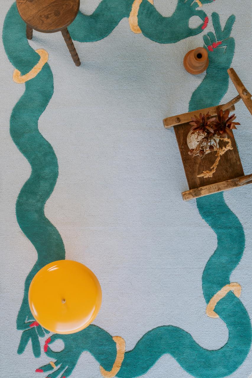 Large blue rug with a green wavy border and subtle gold silk accents