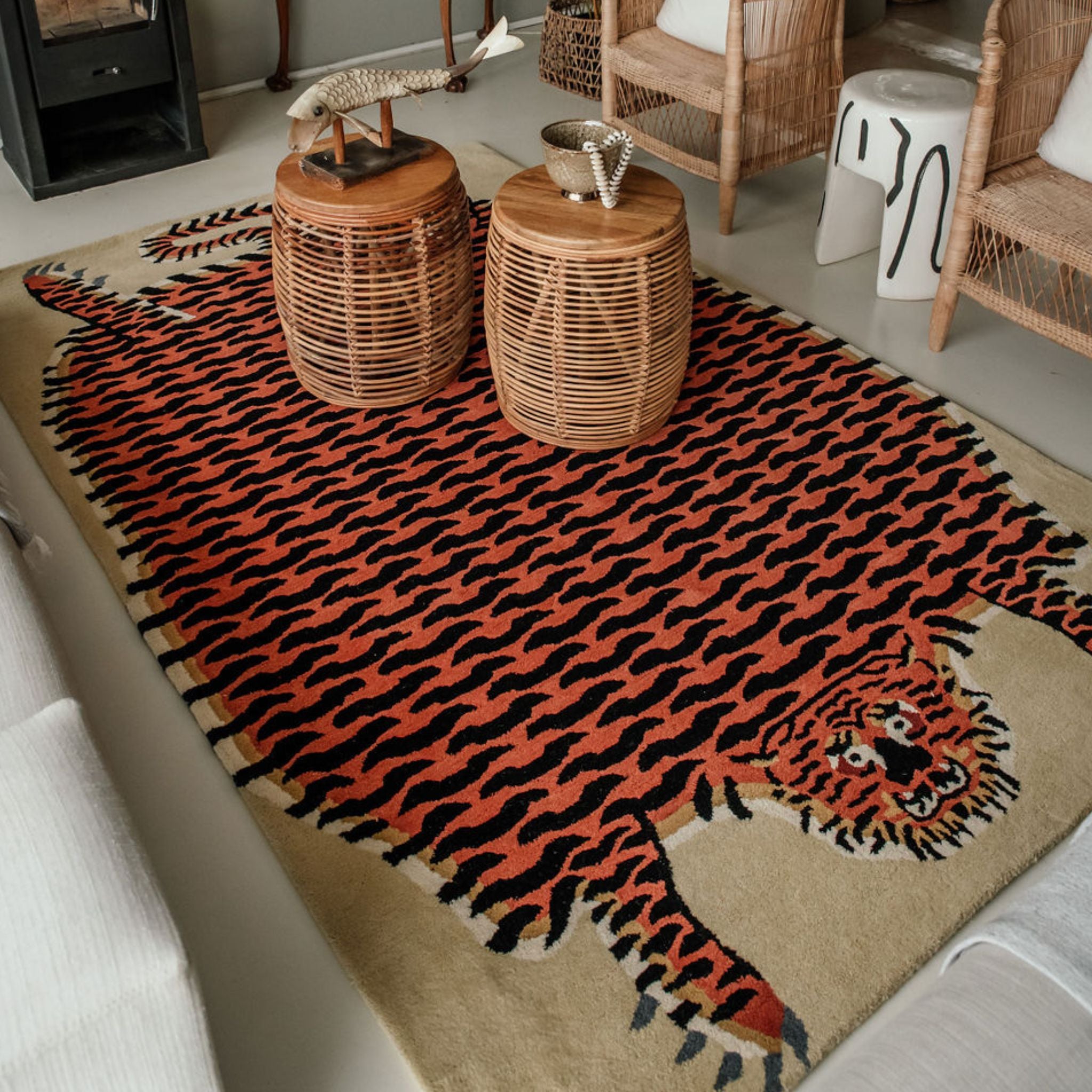 Living room with a large tiger-patterned statement wool rug, wicker chairs, and a fireplace.