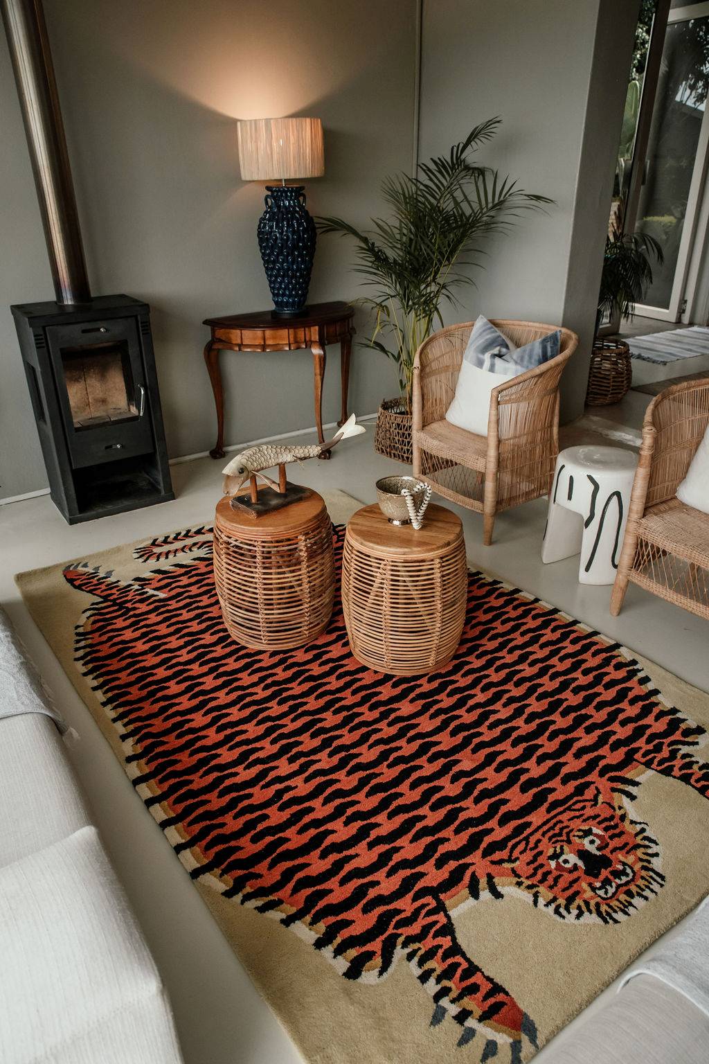 Living room with a large tiger-patterned statement wool rug, wicker chairs, and a fireplace.
