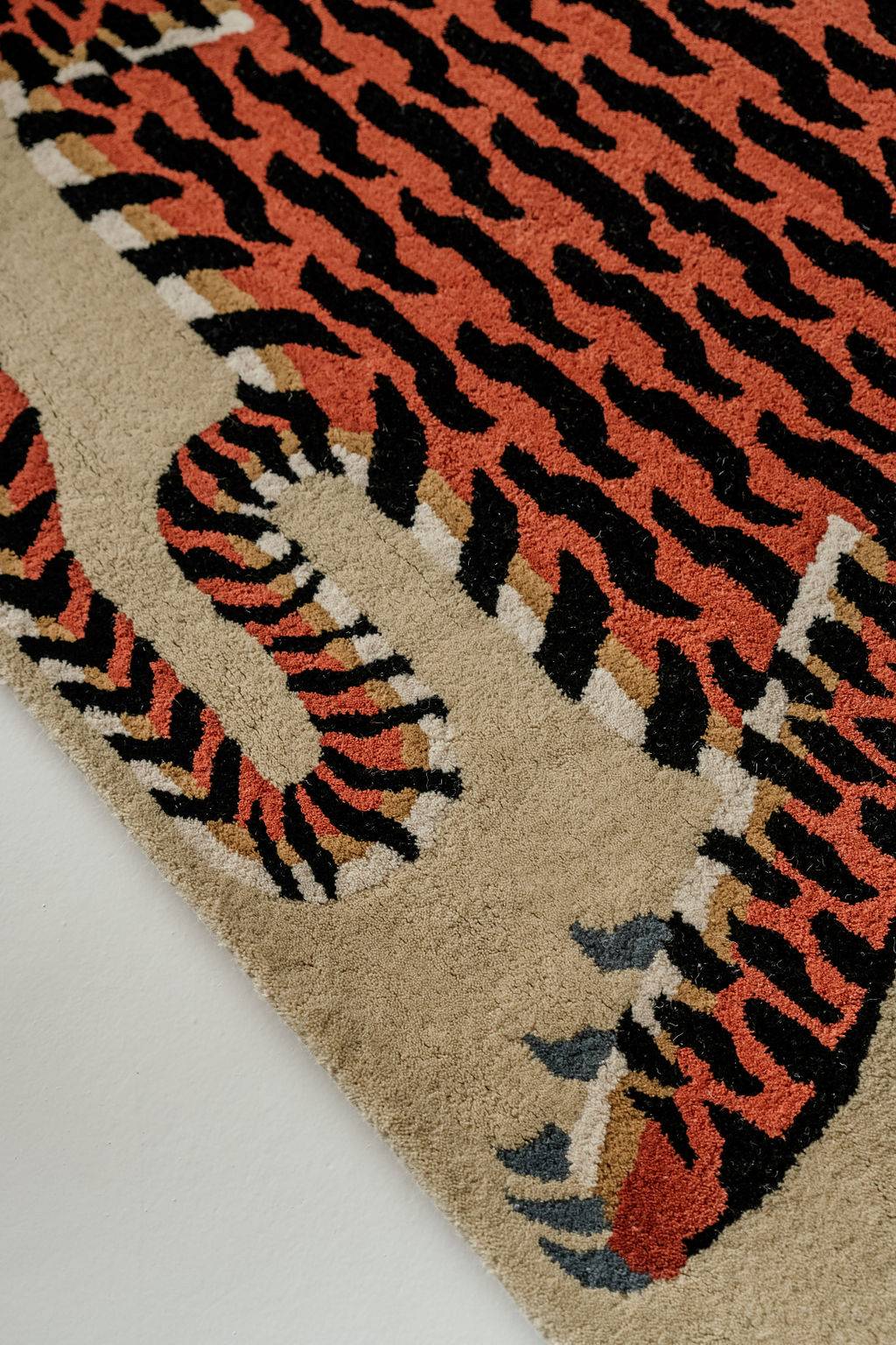Close-up of a tiger print wool rug with orange, black, and beige colors on a white background.