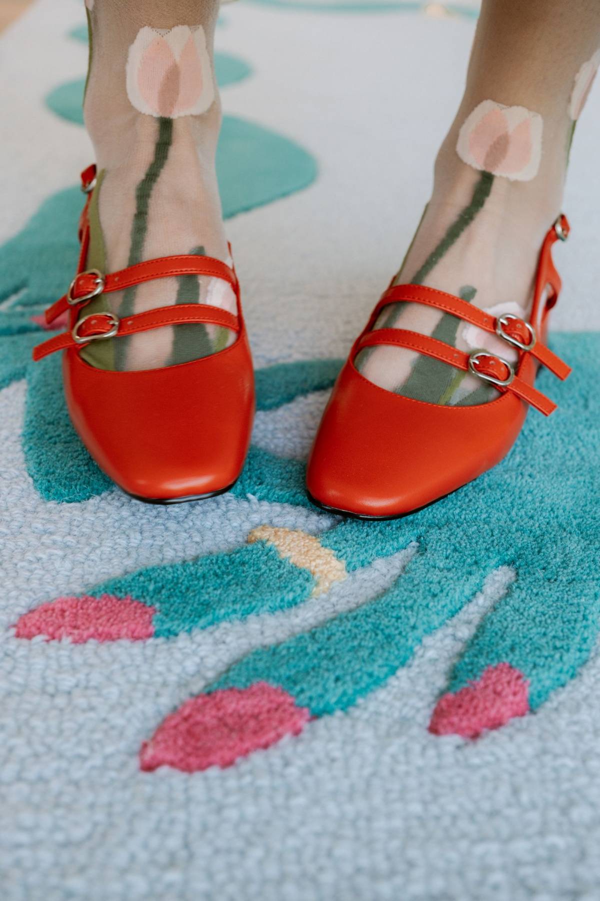 Red shoes worn on a large blue patterned statement rug.
