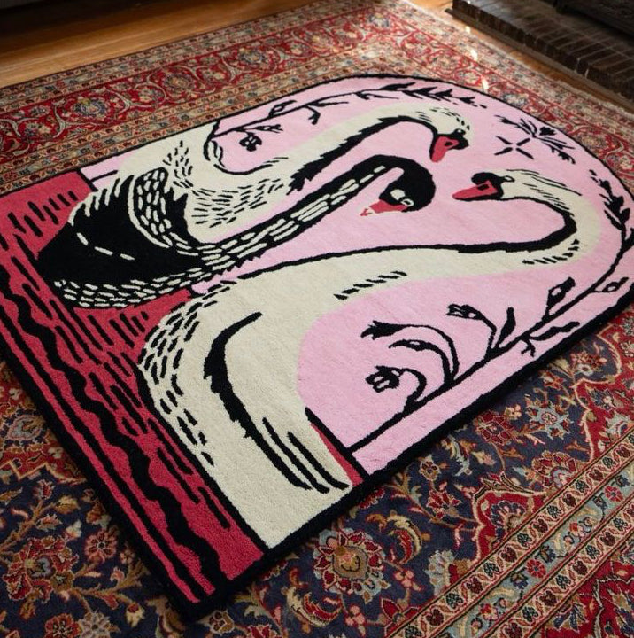 Colorful abstract pink and red rug with swan design on a patterned rug in a living room.